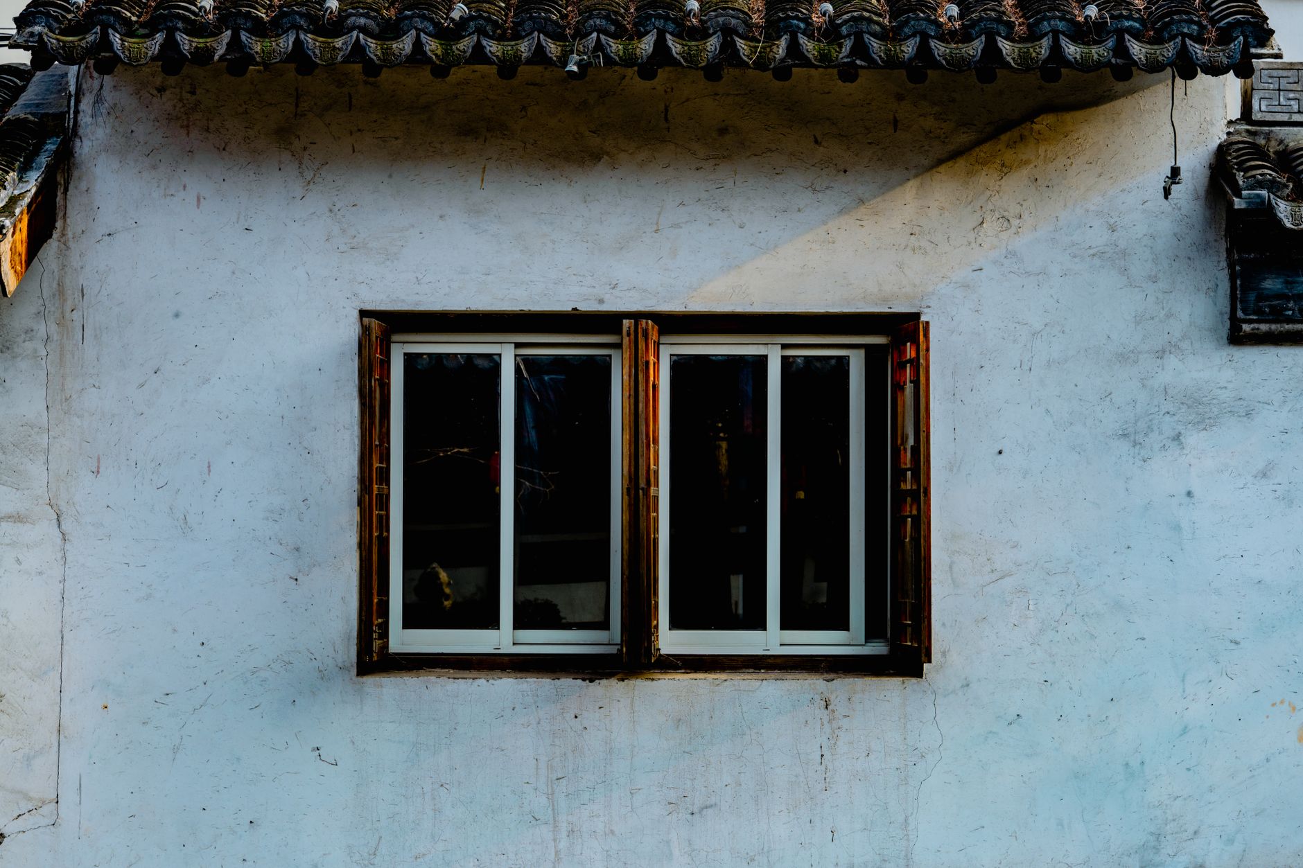 Exterior of aged stone house with wooden ornamented roof and windows with shutters in Riverside, CA